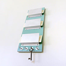 Load image into Gallery viewer, Mail holder piece titled RUE mounted on the wall. This piece includes three holders and key hooks at the bottom. The color of the piece is Soda.